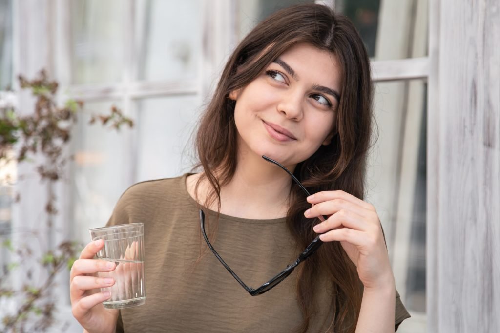 Attractive young woman with a glass of water with sunglasses.